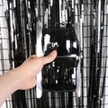 Hand holding a roll of black fringe tinsel curtain for festive party wall decoration - 1*2M / Black