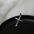 Macro shot of silver stainless steel crucifix pendant on black plate with detailed relief - Silver Cross