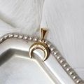 Detail of 18K gold-plated crescent moon pendant on vintage silver tray with white fabric - Gold Horn Crescent Moon