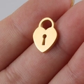 Macro shot of a tiny gold heart-shaped lock pendant held between fingers for size detail - Lock / Gold