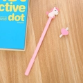 Penna gel unicorno rosa con figura 3D su scrivania in legno con un libro blu - 0.5mm / Rosa