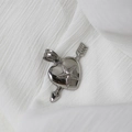 Detailed view of a silver heart pendant with arrow and star patterns on white fabric - Silver Heart