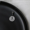 Dettaglio macro del ciondolo medaglia di San Benedetto in argento su espositore nero opaco - Moneta Ritratto Piatta Argento