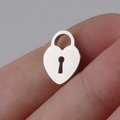 Polished silver heart lock pendant shown on finger to demonstrate the small scale - Lock / Steel