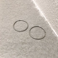Dettaglio di orecchini a cerchio minimalisti in argento su superficie in pietra - Piccolo / Argento