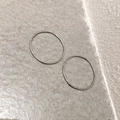 Vista macro di grandi orecchini a cerchio in argento minimalisti su fondo in pietra grigia - Grande / Argento