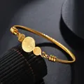 Macro detail of gold St. Benedict medals on a twisted steel rope cuff bracelet - Gold