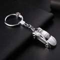 Silver metal car keychain in sleek sports car design on black leather surface - Bright Chrome