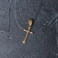 Close-up of a minimalist gold-plated stainless steel cross pendant on a textured dark background - H11 Flat Cross