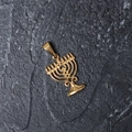Close-up of gold-plated stainless steel Menorah pendant on a grey textured stone surface - H08 Menorah