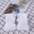 Detail of white faux fur fingerless gloves featuring stylish lace-up ribbons and pom-poms - One Size / White
