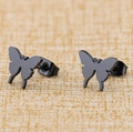 Minimalist matte black butterfly stud earrings in stainless steel on beige background - Black