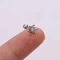 Macro shot of silver starburst stud earring with clear crystal on a fingertip - Starburst Design / Silver