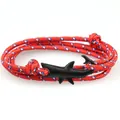 Close-up of a woven red white blue shark bracelet with a matte black shark tail clasp - Red-Blue-White Braided Rope/Black Shark