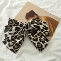 Detail of satin leopard print bow hair clip on a soft white linen fabric background - Black and White Leopard Print