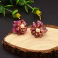 Floral stud earrings with purple stone petals, a white pearl center, and gold accents - Tourmaline
