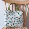 Close-up of small floral canvas tote bag with green handles hanging on a wooden chair - White Floral