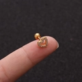 Makroaufnahme eines kleinen goldenen Herz-Ohrsteckers mit Zirkonia auf einer Fingerspitze - Herzstil Gold (No.4 Gold) / 1.2x6mm (Stabdicke x Länge)
