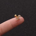 Makroaufnahme von goldfarbenem Edelstahl-Ohrstecker mit Zirkonia, auf der Fingerspitze - Kronenstil Gold (No.10 Gold) / 1.2x6mm (Stabdicke x Länge)