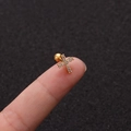 Detailansicht eines vergoldeten Kreuz-Ohrsteckers aus Edelstahl mit Mikrozirkonia-Besatz auf dem Finger - Kreuzstil Gold (No.5 Gold) / 1.2x6mm (Stabdicke x Länge)