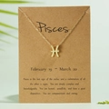 Golden Pisces zodiac symbol necklace on kraft paper card with natural greenery background - Pisces / Gold