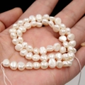 Irregular white baroque freshwater pearls showcased on a palm for size reference - 3-4mm Two-sided Light Horizontal Hole High Luster / Natural White