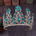 Close-up of golden bridal tiara with emerald green gems and clear rhinestones - KC Gold Olive Green Rhinestone