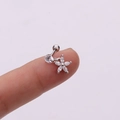 Macro shot of silver flower tragus piercing with clear zircons held on a fingertip - Floral Round Zirconia (Silver 7#)