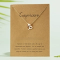 Gold Capricorn symbol pendant necklace on kraft paper card with constellation date info - Capricorn / Gold