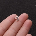 Macro di un orecchino huggie a forma di fiocco argento con micro zirconi incastonati - Stile Fiocco (1#)