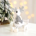 White plush Christmas reindeer doll with silver sequins sitting on a bench with bokeh lights - Silver Reindeer
