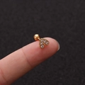Nahaufnahme eines goldenen Herz-Ohrsteckers mit Kristallen auf einer Fingerspitze - Herz Gold Stil (No.16 Gold) / 1.2x6mm (Stabdicke x Länge)