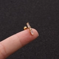 Nahaufnahme von goldenem 16G Edelstahl-Ohrstecker mit drei klaren Zirkonia-Steinen - Rechteckiger 3-Stein-Stil (No.17 Gold) / 1.2x6mm (Stabdicke x Länge)