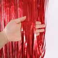 Mano che tiene la tenda a frange rosso opaco per decorazioni di feste e compleanni - 1x3 Metri / Rosso Opaco