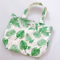 Detailed view of white cotton tote bag featuring green tropical leaf prints and zipper closure - Banana Leaf Style
