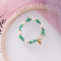 Detail shot of bohemian beaded bracelet featuring green stones, pearls and shell charms - Green