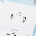 Astronaut silver stud earrings with black and orange details on white card display - White Gold Plated Copper