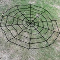 Large black round spider web decoration made of thick rope on green outdoor grass - 2.5m Round Black Web