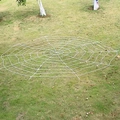 Large white circular spider web prop laid on green lawn for Halloween party decoration - 5m Round White Web