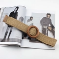 Detail of khaki woven elastic belt featuring a round dark brown wooden buckle on a magazine - Round Pinless Wood Buckle / Khaki