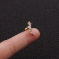 Detailed close-up of a tiny gold leaf ear stud with white zircons held on a fingertip - Multi-shape Zirconia Combo (5#)