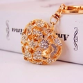 Golden heart-shaped rhinestone keychain with hollow design on a minimalist book background - Individual Packaging / White