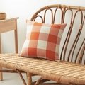 Square orange and white checkered linen pillow cover placed on a rattan bench - Orange Large Gingham