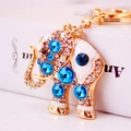 Gold elephant keychain with blue crystals and white enamel on a white book edge - Blue Gemstone Elephant