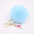 Blue faux fur pompom keychain with golden flamingo charm and pearl accents on white background - Light Blue
