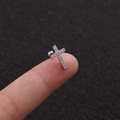 Dettaglio dell'orecchino a lobo a croce d'argento con zircone lucido tra le dita - Stile Croce d'Argento (Argento 4#)