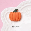 Macro di una zucca in resina opaca arancione 18x18mm su un piatto bianco con rilievi - Zucca