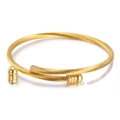 Dettaglio di un bracciale rigido a cavo ritorto dorato con estremità a sfera decorative - Oro