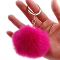 Vibrant bright pink faux rabbit fur pom-pom keychain with gold chain held in palm - 7cm Pom-pom / Rose Red