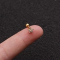 Flower zircon stainless steel stud earring with gold finish shown on a fingertip - Gold
